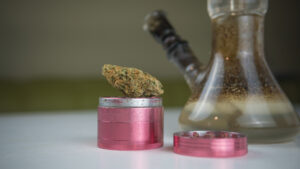 Close-up of dirty bong and grinder with medical marijuana buds on the white table. Smoking cannabis with water pipe. barcelona weed club